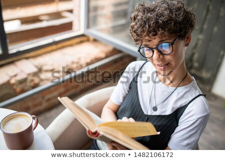 Zdjęcia stock: Young Woman With Short Curly Brown Hair And Reading Book At Home