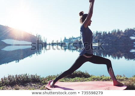 Foto d'archivio: Woman Meditating In Yoga Pose In Front Of Mountain Lake