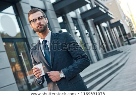 Stok fotoğraf: Elegant Young Man Wearing Glasses And Suit Holding Collar