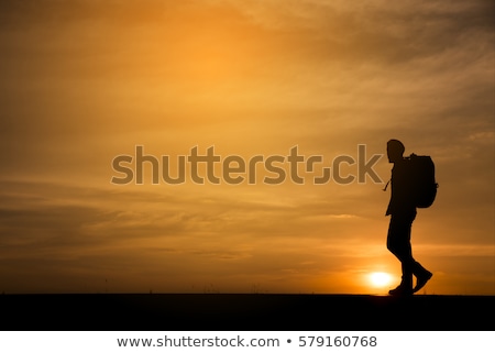 Foto d'archivio: Silhouette Of A Backpacker Man At Sunset