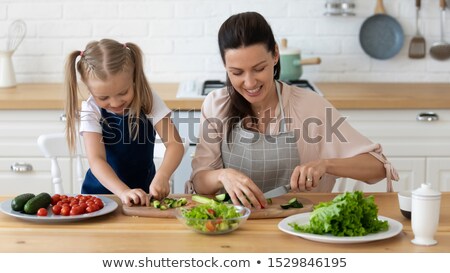 Foto stock: Smiling Woman Cutting Vegetables On Chopping Board