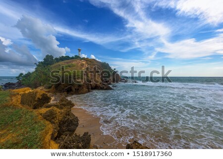 [[stock_photo]]: Old White Lighthouse On The Rocky Sand Hill