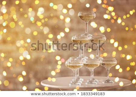 Stockfoto: Sparkling Champagne Pyramid Tower Of Glasses At The Party In Front Of Golden Wall
