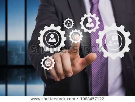 Foto stock: Business Man Interacting With People In Cogs Graphics Against Grey Background