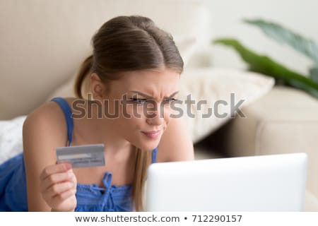 Stok fotoğraf: Worried Young Woman With Credit Card And Laptop