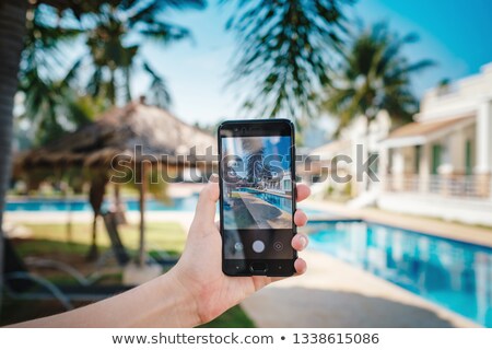 Stock fotó: Hand Holding Phone On Background Of The Pool In Hotel Photo Camera On The Screen Close Up Hand Hol