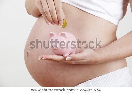 Stock fotó: Close Up Of Pregnant Woman Putting Coin Into Piggy Bank