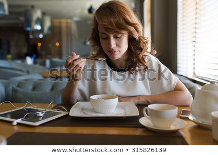 ストックフォト: Brunette In A Cafe Drinking Tea Eating Sweets Reading A Book Looking At The Camera Beautiful Ey