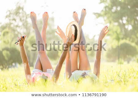 Foto stock: Women In Straw Hats Lie On Grass Lawn