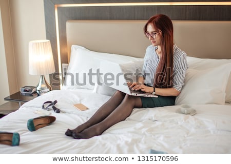 Foto d'archivio: Beautiful Red Haired Woman In Suit Relaxing With Her Laptop While Having Her Breakfast In The Kitche