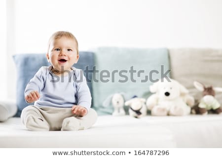 Foto d'archivio: Adorable Laughing Baby Boy Sitting On Sofa And Looking Up