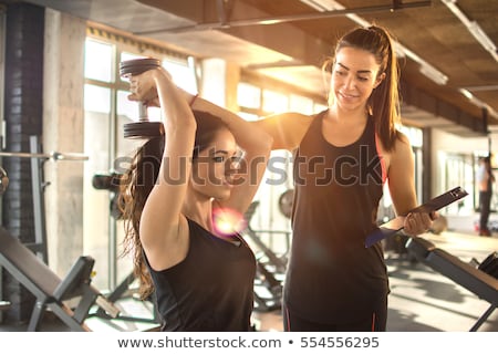 Stok fotoğraf: Woman Exercise In A Gym With The Help Of Her Personal Trainer