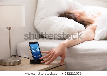Foto stock: Woman Turning Off Alarm