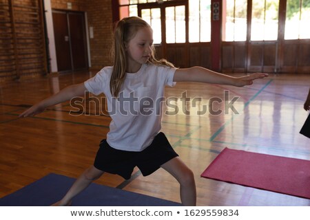 Foto d'archivio: Front View Of Schoolgirl Doing Yoga Position On A Yoga Mat In School Gymnast