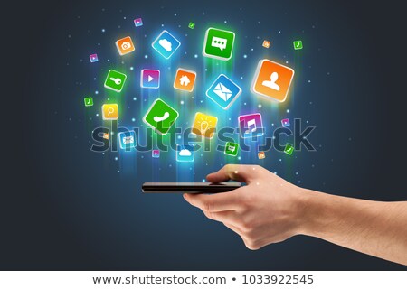 Foto stock: Hand Using Phone With Application Icons Flying Around