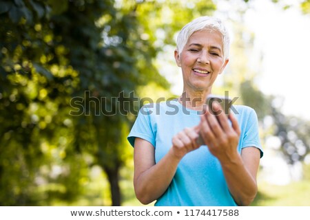 Stockfoto: Sporty Senior Woman Using Mobile Phone In The Park