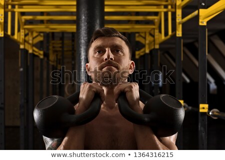 Сток-фото: Focused Bodybuilder Lifting Up Kettlebells Looking At Camera