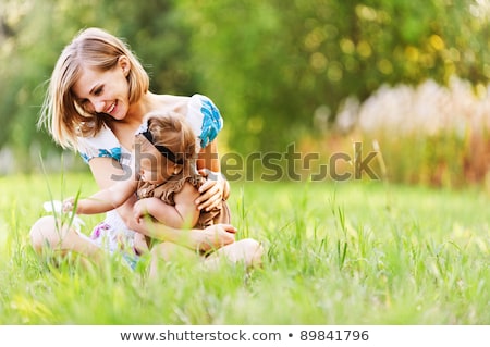 Stock fotó: The Young Mother And Daughter On Green Grass Background