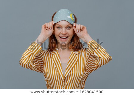 Stock foto: Ginger Female Model Wears Sleepmask And Striped Pajamas Awakes In Good Mood Realizes Today Is Week