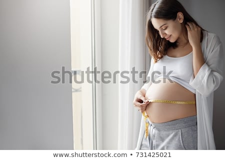 Foto stock: Pregnant Woman Measures Her Belly With A Measure