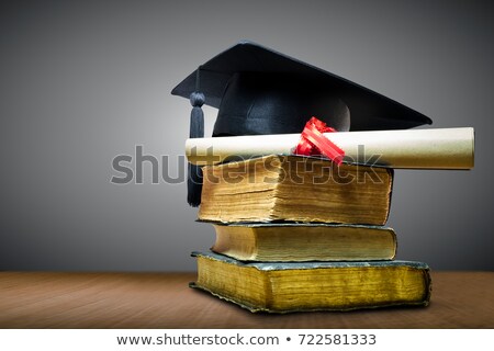 Stok fotoğraf: Graduation Mortarboard On Top Of Stack Of Books On The Wooden Ta