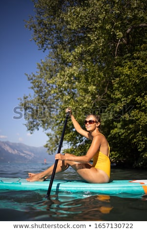 Foto stock: Pretty Young Woman Paddle Boarding On A Lovely Lake
