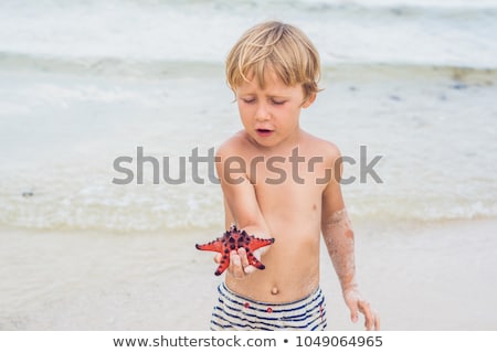 ストックフォト: A Boy And A Red Starfish Against The Backdrop Of The Sea