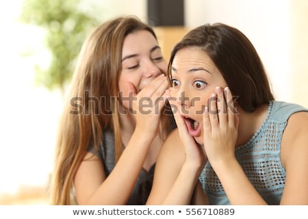 Stockfoto: Young Woman Whispering A Secret Into Her Friends Ear