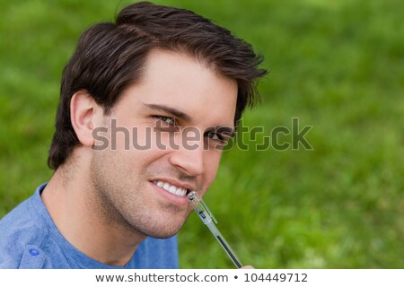 Stock foto: Young Thoughtful Man Looking Straight At The Camera While Holding His Ballpoint Pen