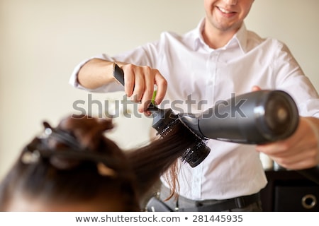 Stockfoto: Happy Stylist With Fan Making Blow Dry At Salon