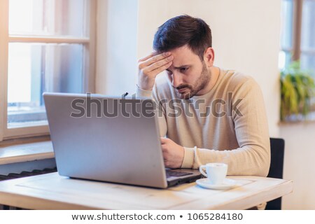 Foto stock: Upset And Worried Young Businessman Sitting And Working At Lapto