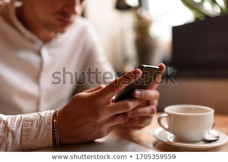 Stock fotó: Cropped Photo Of Young Man In White Shirt Holding Smartphone Wh