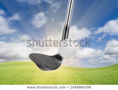 Stockfoto: Black Golf Club Wedge Iron Hitting Golf Ball Against Grass And B