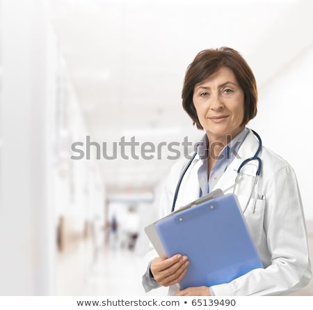 Stock fotó: Female Doctor In Hospital Corridor Holding Clipboard