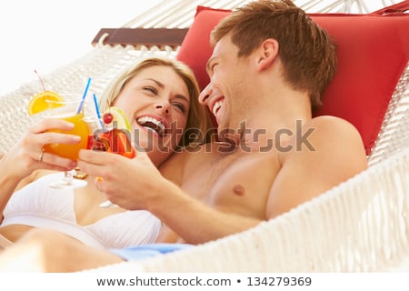 Foto stock: Young Holiday Couple Relaxing In A Hammock