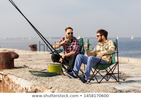 Stockfoto: Happy Friends Fishing And Drinking Beer On Pier