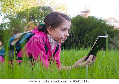 Stock fotó: Teen Girl With Electronic Book Laying On Grass