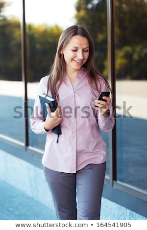Stock photo: Young Businesswoman With Cellphone And Organizer While Standing