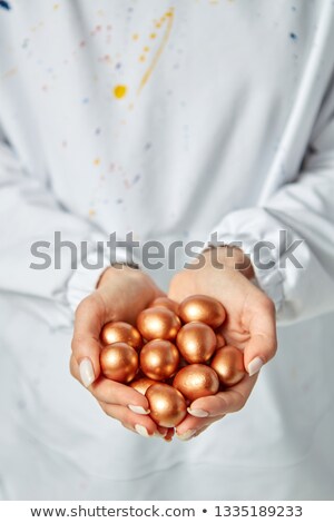 Stock fotó: Closeup A Lot Of Golden Painted Little Eggs The Girls Hands Are Holding On Gray Background With Cop