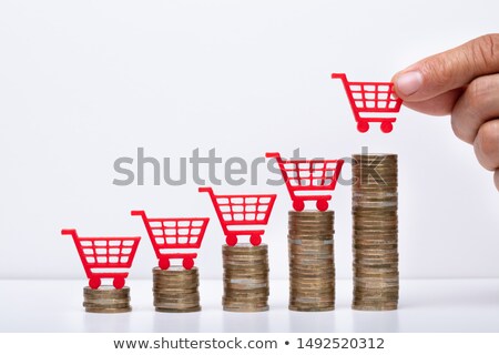 Zdjęcia stock: Businessman With Shopping Cart And Coin Stacks In Office