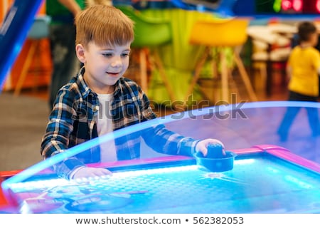 Zdjęcia stock: Boy Standing And Playing Air Hockey Game At Amusement Park