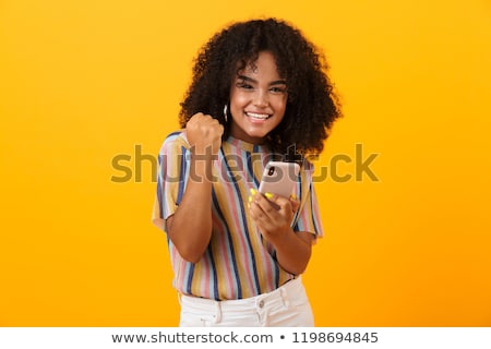 Foto stock: Happy Emotional Young Women Friends Posing Isolated Over Yellow Background Using Mobile Phones