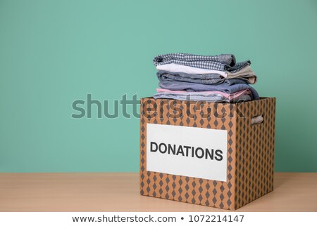 Foto d'archivio: Donation Box With Clothes On Wooden Table