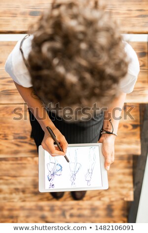 Young Female Fashion Designer Pointing At One Of Model Sketches Foto stock © Pressmaster