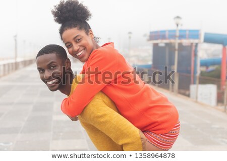 Zdjęcia stock: Portrait Of Strong African American Man Carrying Mixed Race Woman Piggyback At Pavement They Are Sm