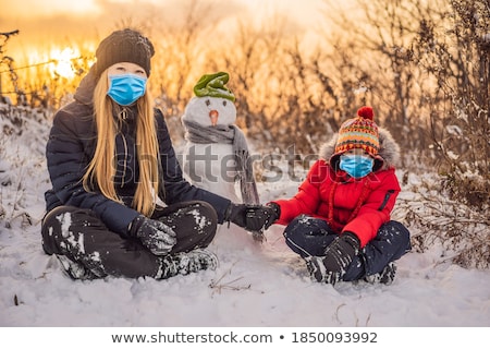 Foto stock: Happy Family In Warm Clothing Smiling Mother And Son Making A Snowman Outdoor The Concept Of Winte