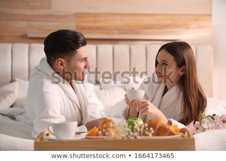 Stock photo: Smiling Young Man Wearing Bathrobe Having Breakfast