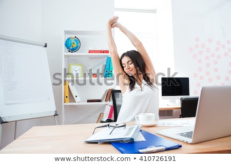 Zdjęcia stock: Businesswoman Sitting At The Table In Office And Stretching Her