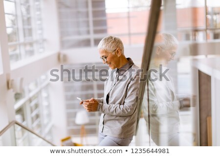 Foto stock: Senior Businesswoman Using Mobile Phone In Modern Ofice