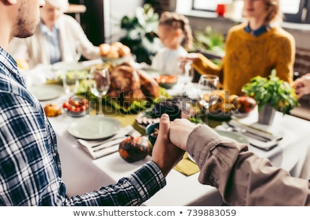 Stockfoto: Family Holding Hands At Dinner Table